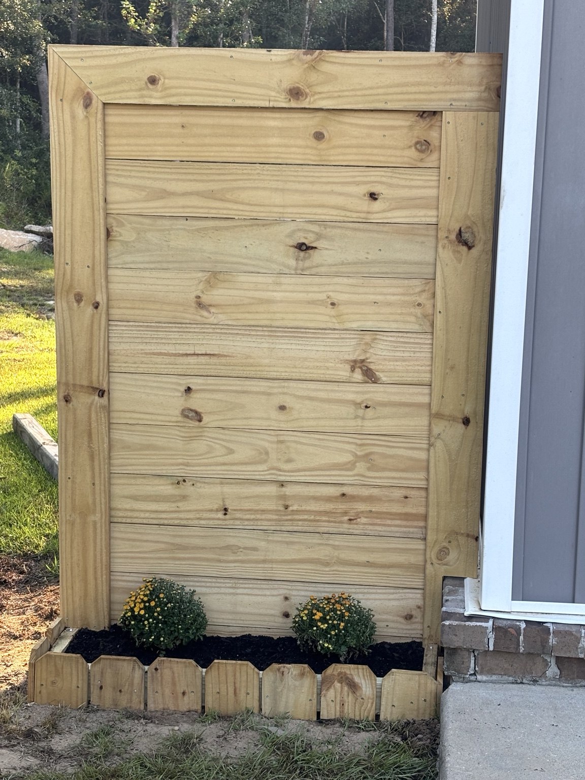 Wood privacy screen with horizontal boards and a flower bed